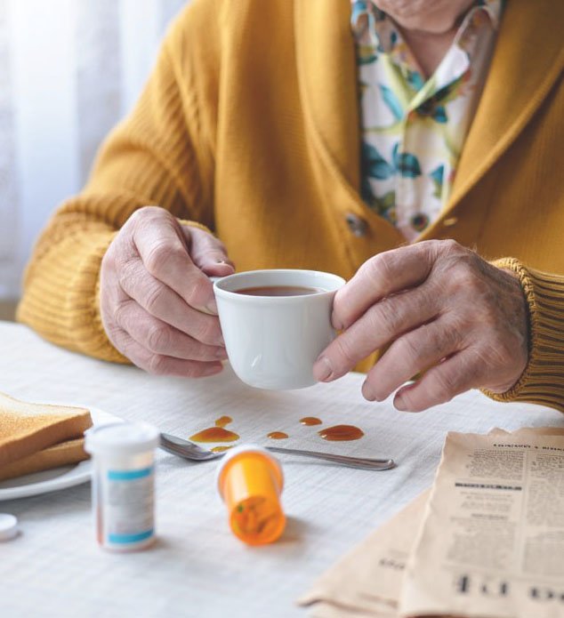 Пожилая женщина с болезнью Паркинсона пьет чай